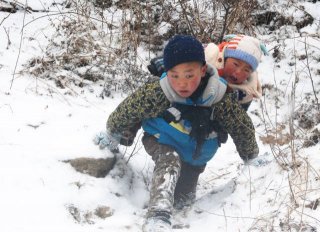 男孩冒雪背弟弟搬新家 走50分钟山路
